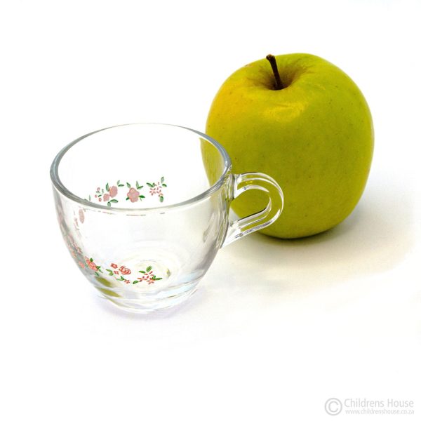 The featured image of a transparent glass cup with a floral design, next to an apple - this visually illustrates the size of the cup.