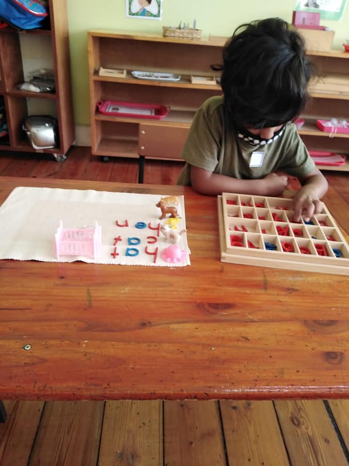 A 5 year old learner working with the Montessori Small Alphabet letters, learning to write words.