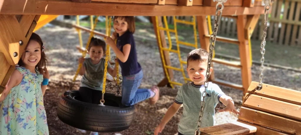 Country Meadows Montessori School - Primary Guide - the picture is of Primary aged children, playing outdoors on a wooden climbing structure.