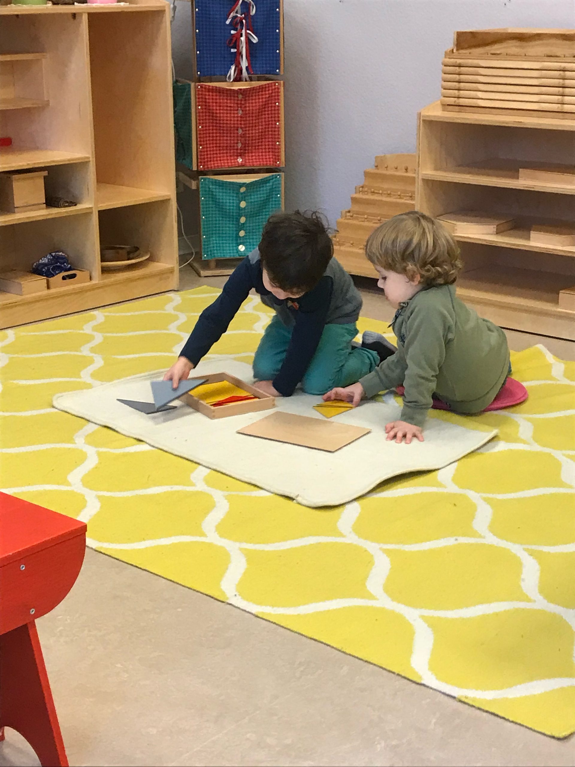 Two Children working together with the Constructive Triangles on a floor mat